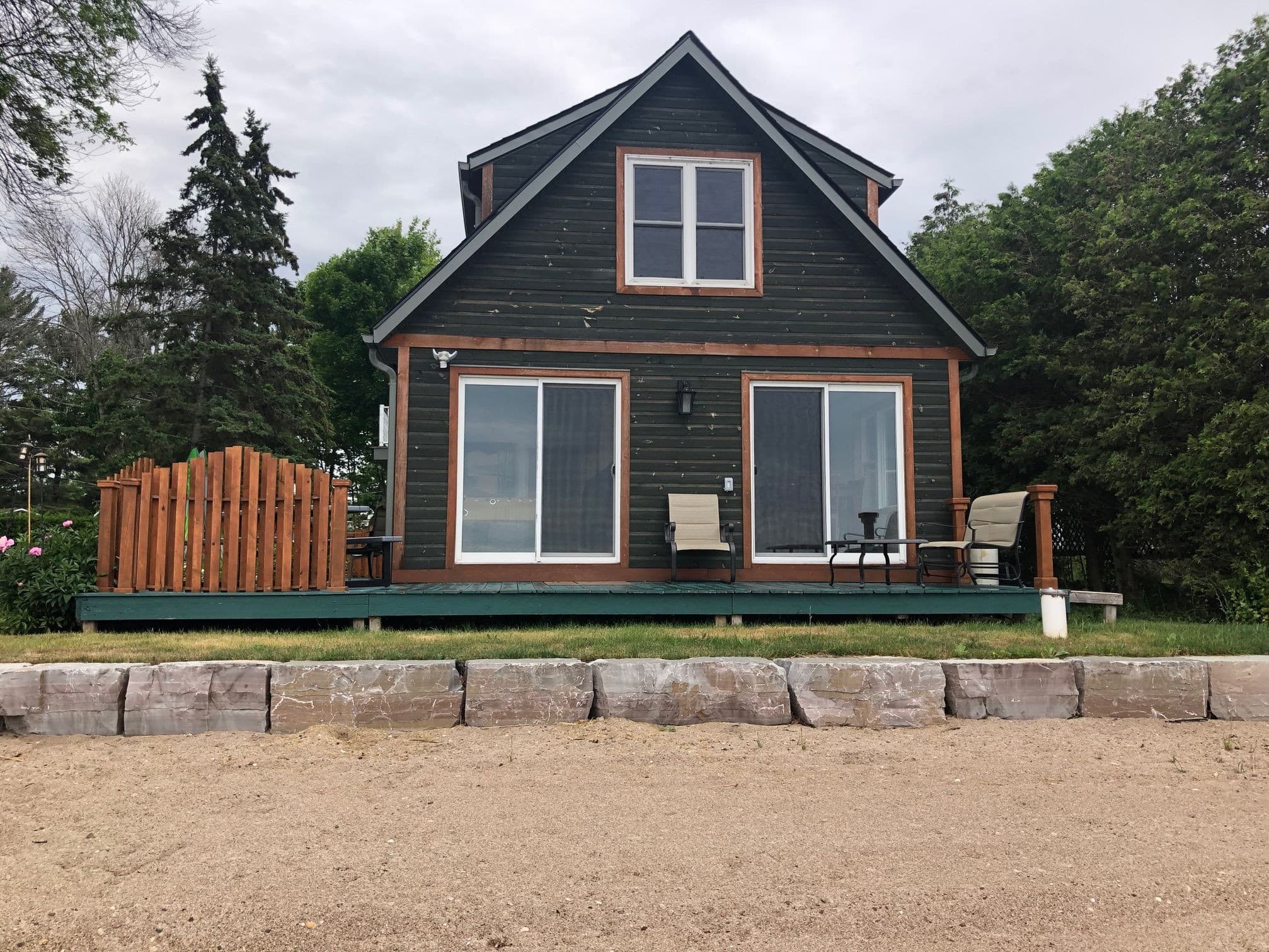 Exterior view of a cottage at Harmer's Cottages with lawn and waterfront setting.