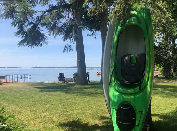 Kayak near the waterfront lawn and chairs at Harmer's Cottages.